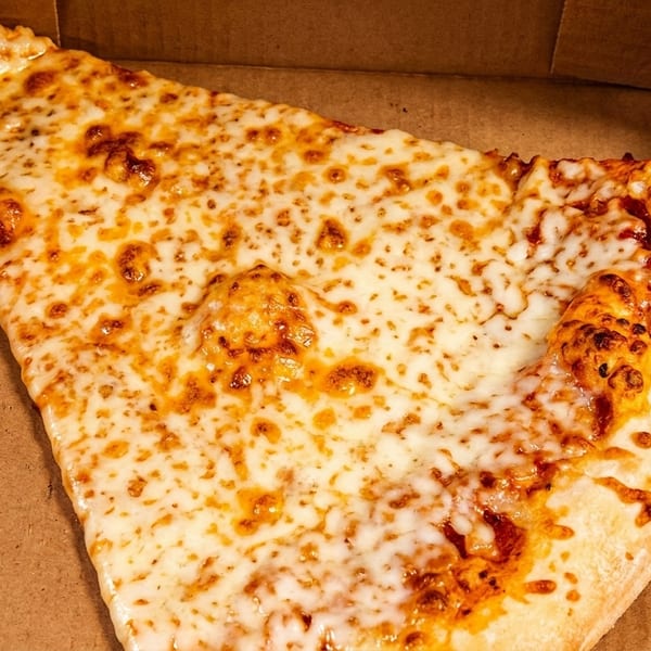 A large, cheesy slice of pizza with a golden-brown crust sits in a cardboard box.